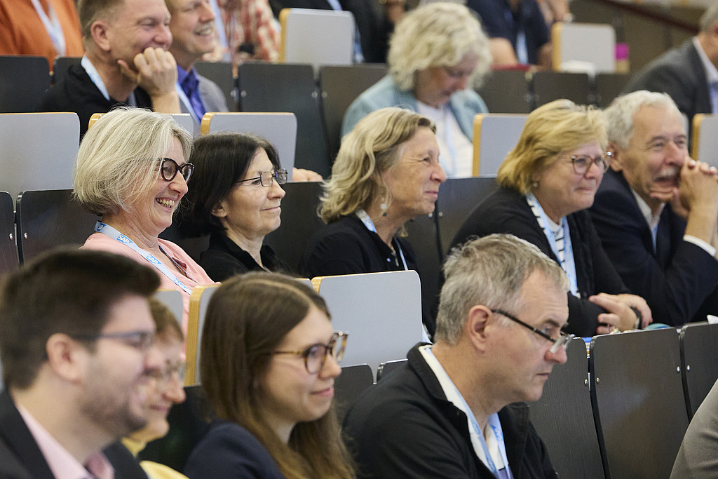 Foto eines Publikums: Die Gäste lächeln und lauschen dem Programm.