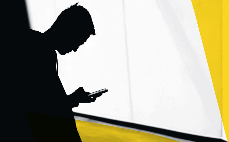 Ein Mann steht in einem dunklen Gang und schaut auf sein Handy herab