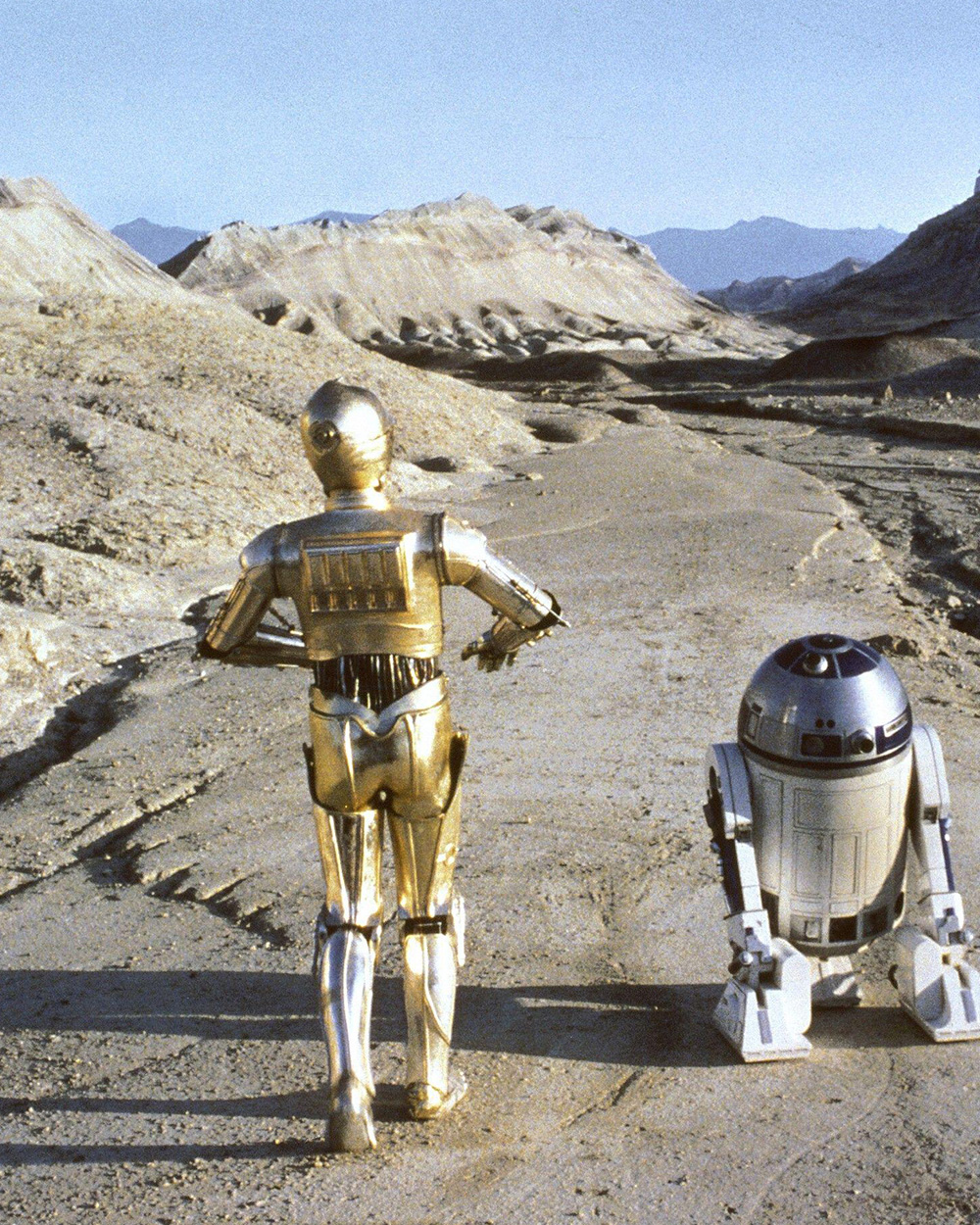 Die Star-Wars-Charaktere C3PO und R2D2 laufen eine Wüstenstraße herunter