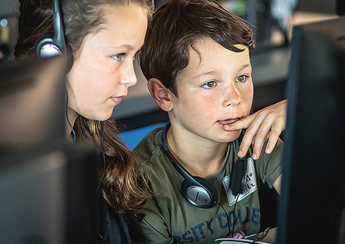 Zwei Kinder schauen gemeinsam auf den Desktop eines Computers