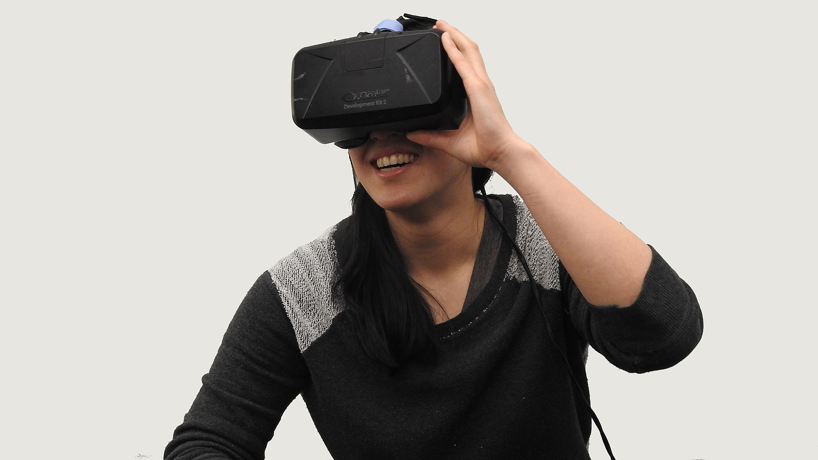 Eine junge Frau trägt eine VR-Brille und lacht