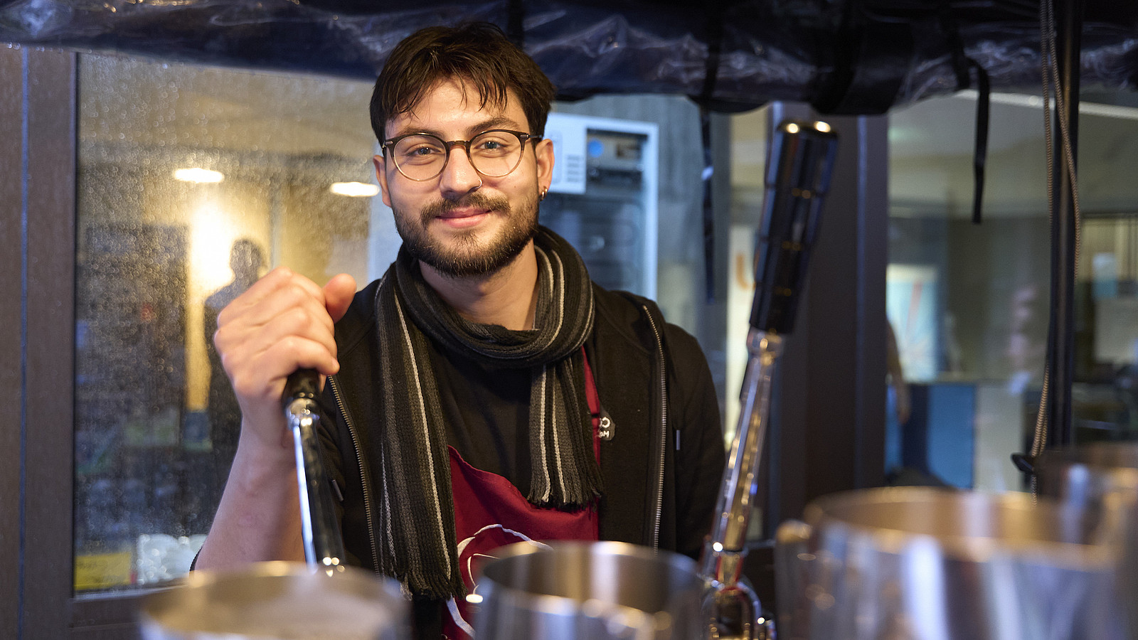 Ein Barista am Kaffeestand lächelt in die Kamera