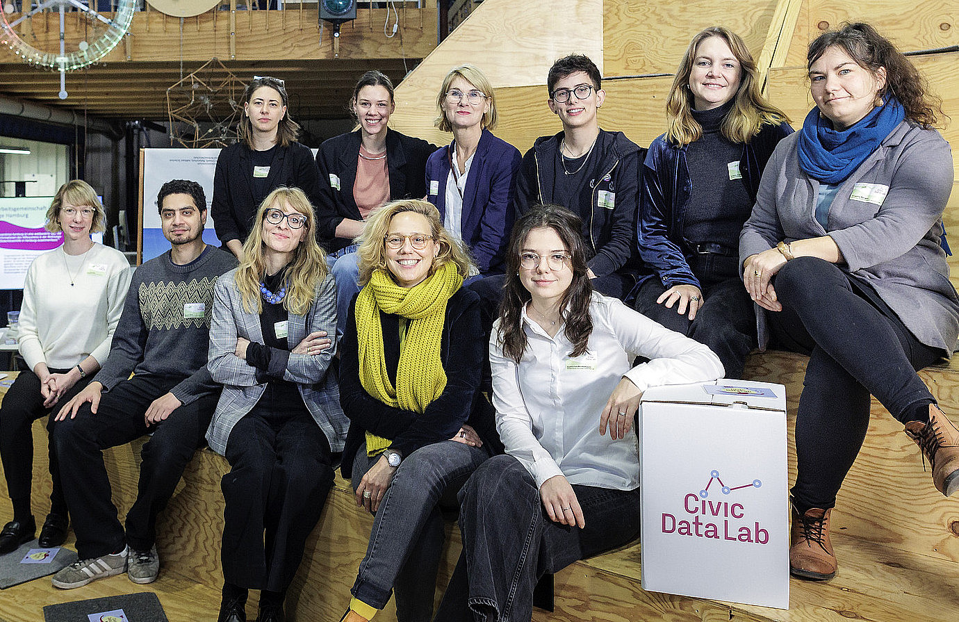 231124_SCARITAS_PHT003.jpg Das Team des Projekts: mehrere Personen sitzen auf einer Holztribüne