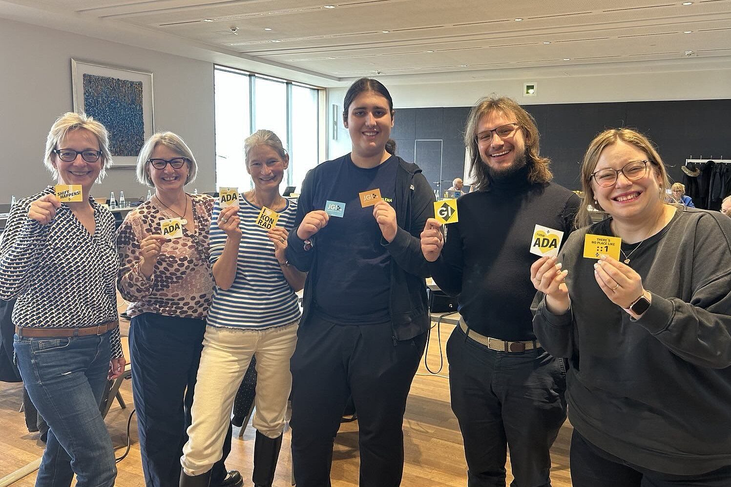 sechs fröhliche GI-Präsidiumsmitglieder bei einem Treffen in Siegburg: GI-Präsidentin Christine Regitz, Claire Zschiesche, Geschäftsführerin Cornelia Winter, Marlena Müller, Stefan Hildebrand, Katharina Weitz. Alle halten einen Sticker der GI in der Hand.
