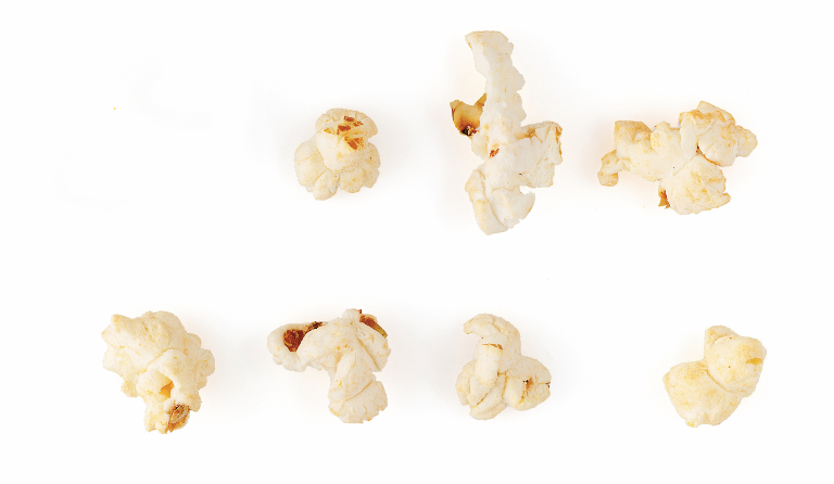 Einzelne Popcorn, in Reihen angeordnet. Eines fällt aus der Reihe und hat sich ins gegenüberliegende Impressum verirrt.