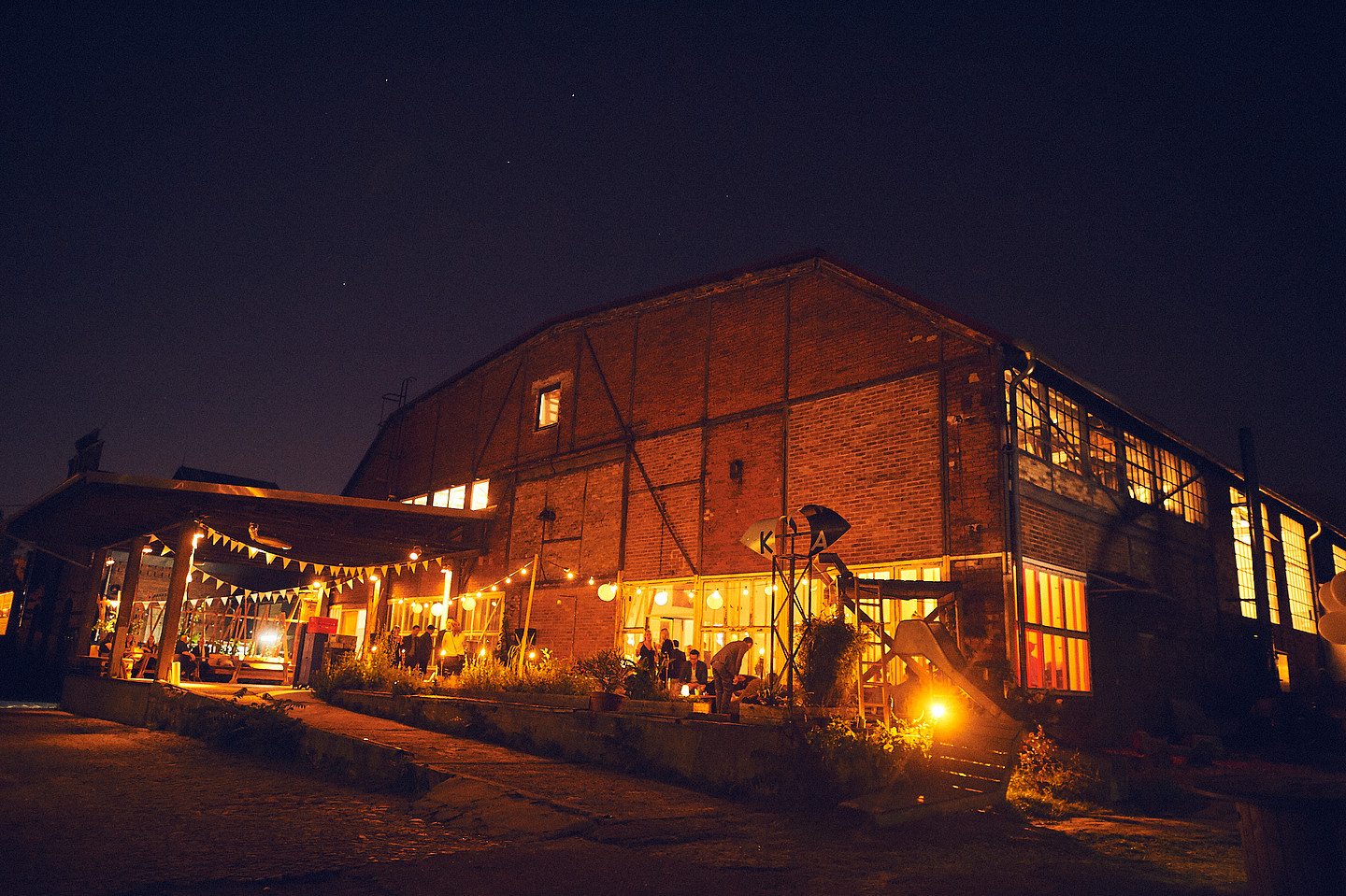 Ein großes Backstein-Industriegebäude, bei Nacht, hell erleuchtet