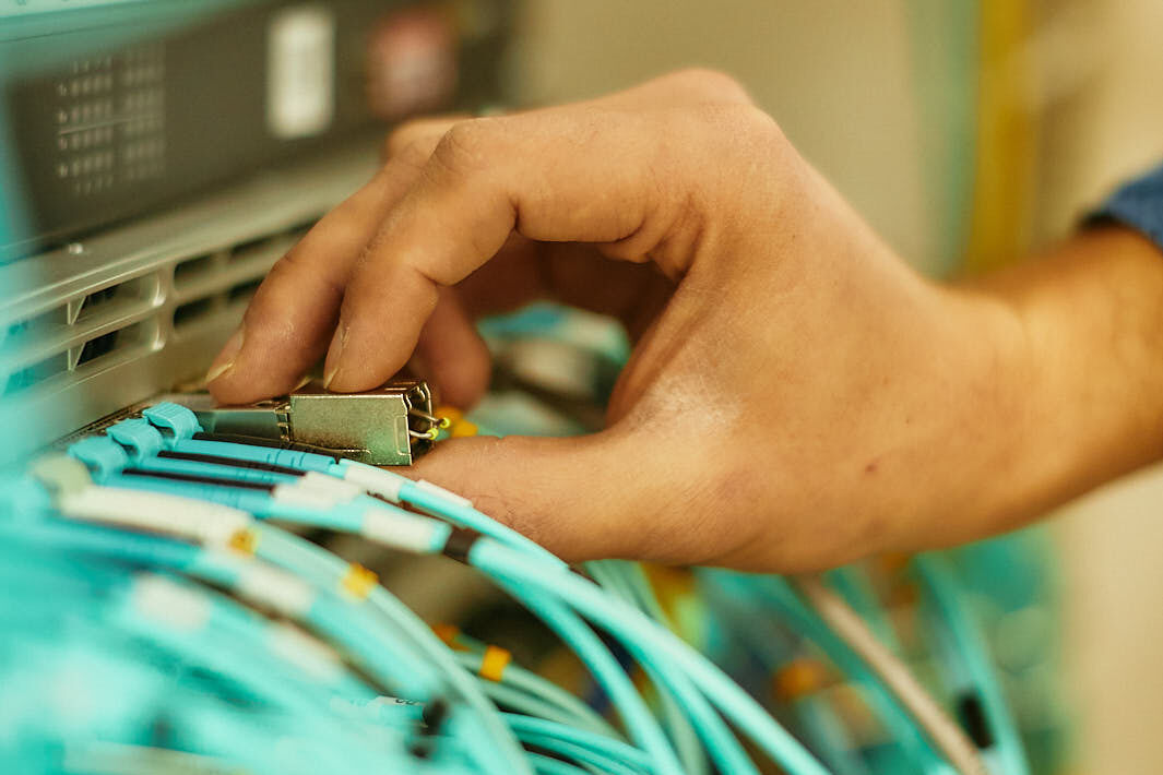 Eine Hand steckt einen Stecker in einen Server